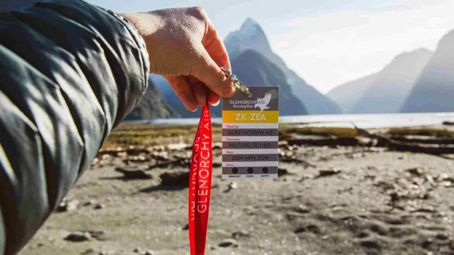 Glenorchy Air boarding pass held up with Mitre Peak in the background