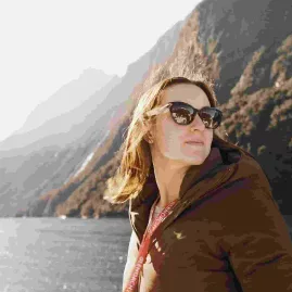 Woman enjoying the fresh air and views of Milford Sound during a nature cruise.
