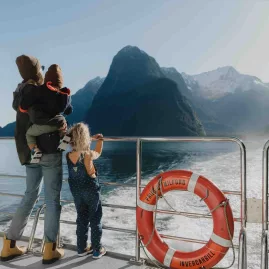 Family enjoying the view of Mitre Peak from the deck of a cruise boat in Milford Sound.