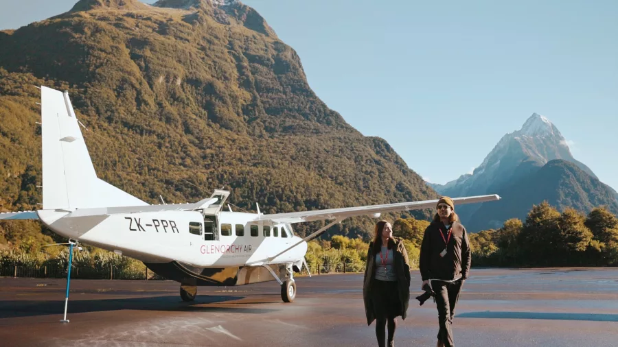 Couple walking away from Glenorchy Air plane after landing in Milford Sound