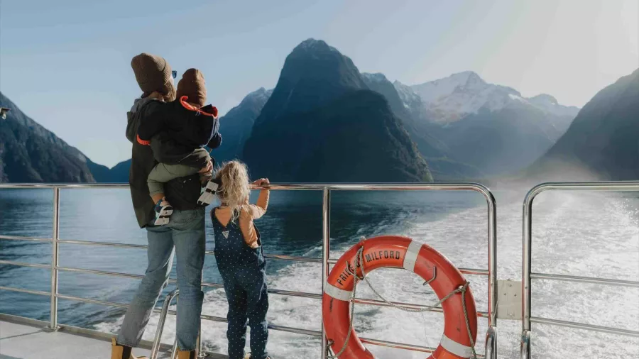 Family enjoying the view of Mitre Peak from the deck of a cruise boat in Milford Sound.