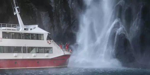 Southern Discoveries cruise boat beside Stirling Falls in Milford Sound.