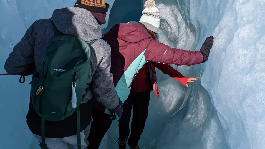 Hikers entering a narrow ice tunnel during a Mount Cook heli hike