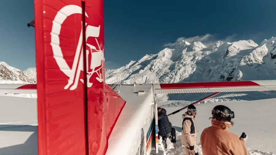 Skiers next to a ski plane with views of Aoraki Mount Cook in the background