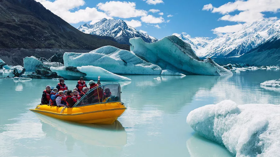 Yellow boat navigating through floating icebergs on Tasman Lake near Mount Cook