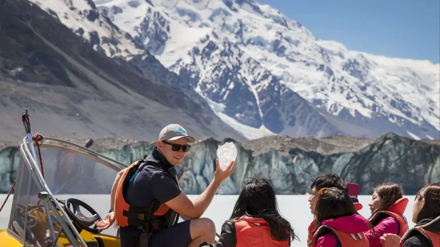 Guide showing glacier ice to passengers on a Tasman Lake boat tour