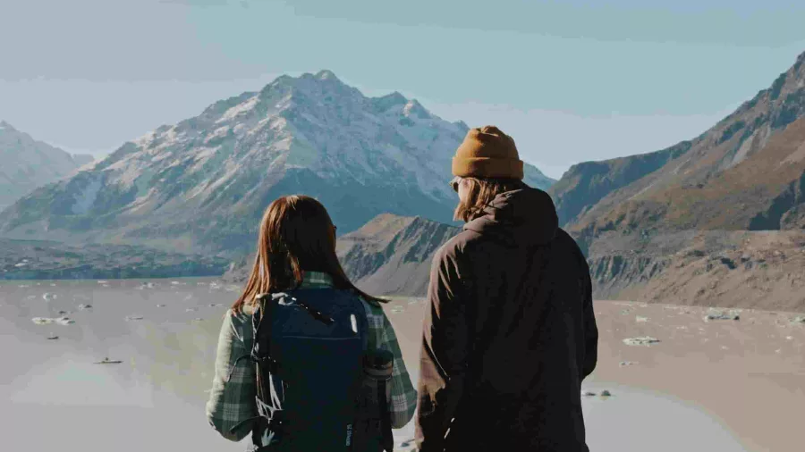 Couple admiring Tasman Glacier Lake and floating icebergs from a lookout point