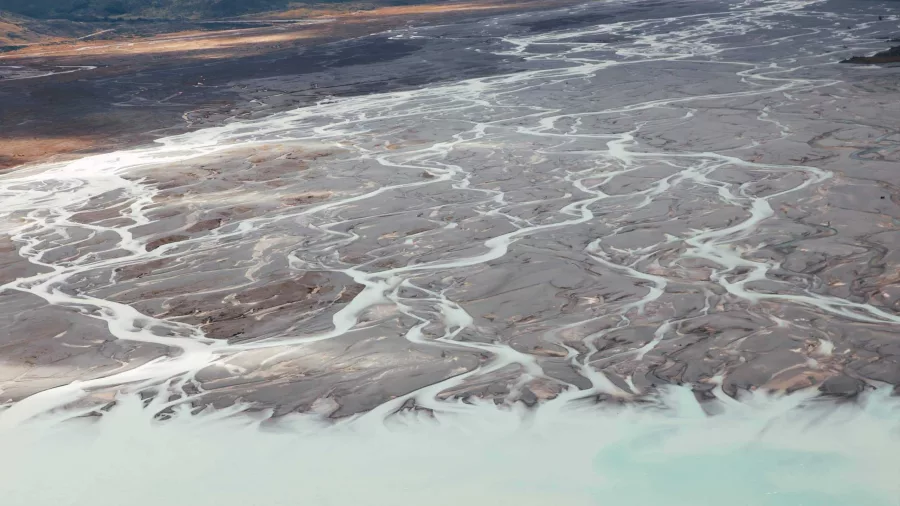 Aerial view of braided rivers flowing into a turquoise glacial lake in Mount Cook National Park