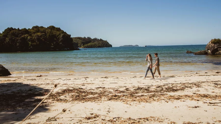 Couple walking along the shoreline of Bathers Beach, Stewart Island