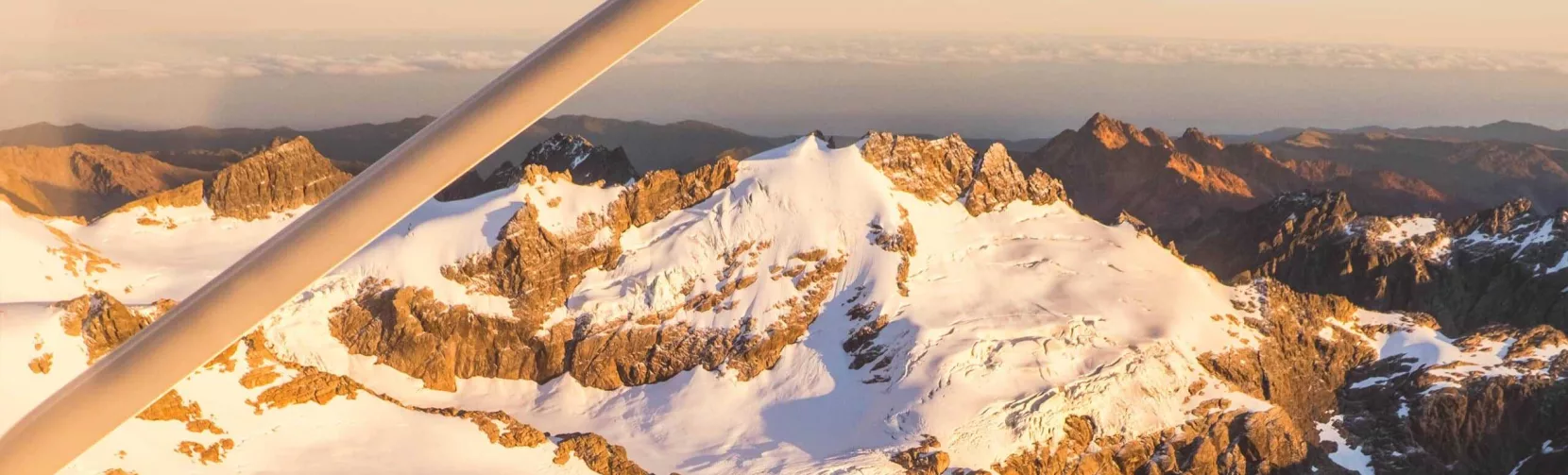 Snow-dusted peaks of Mt Aspiring National Park glowing in sunrise light