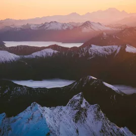 Layers of snow-capped peaks and alpine lakes at sunrise in the Southern Alps
