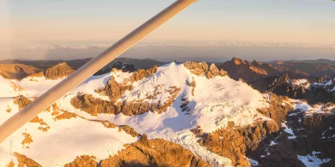 Snow-dusted peaks of Mt Aspiring National Park glowing in sunrise light
