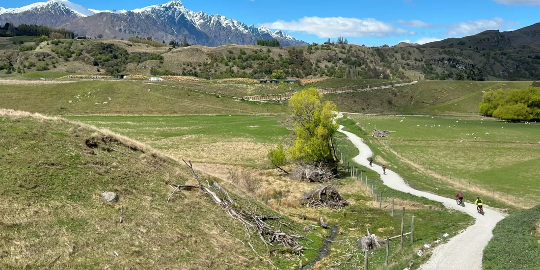 Cyclists on the Wharehuanui Trail with snow-capped peaks in the background