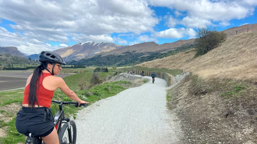 Woman biking along the Wharehuanui Trail on a sunny day during Ale Trail tour