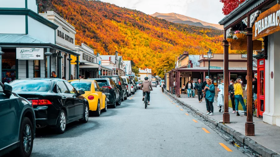 Cyclist rides down Arrowtown’s historic main street during autumn on the Ride to Riches tour
