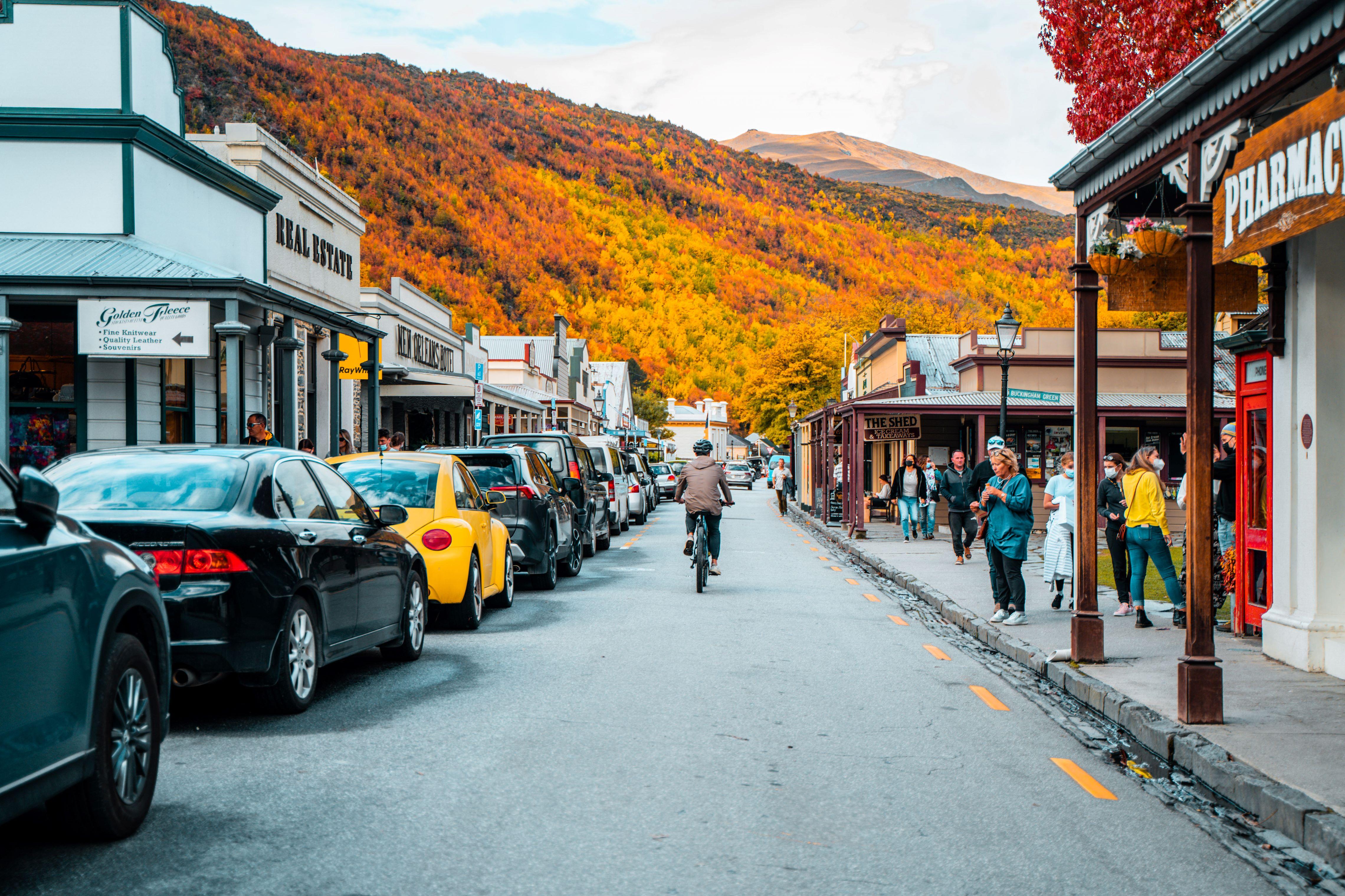 Cyclist rides down Arrowtown’s historic main street during autumn on the Ride to Riches tour