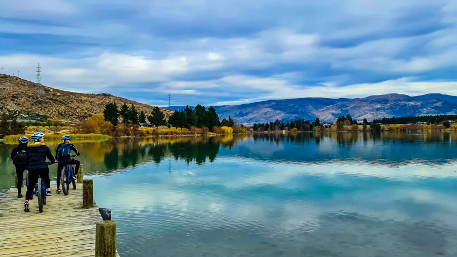 Cyclists on a wooden pier over Lake Dunstan near Cromwell with reflections in the water
