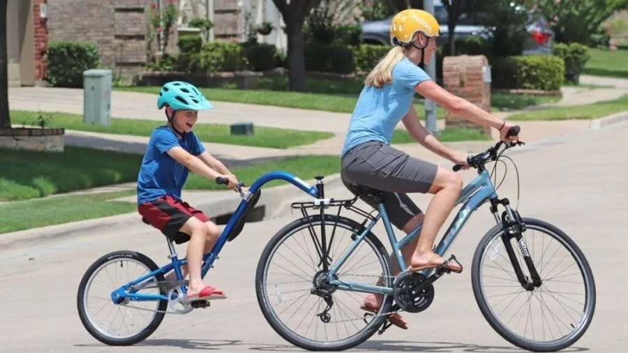 Woman and child riding a tow bike on a quiet residential street in Queenstown