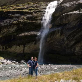 Couple standing beneath a waterfall at Earnslaw Burn
