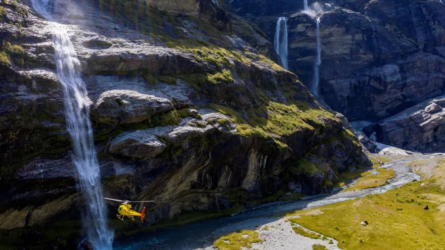 Helicopter flying beneath waterfalls near Earnslaw Burn Glacier