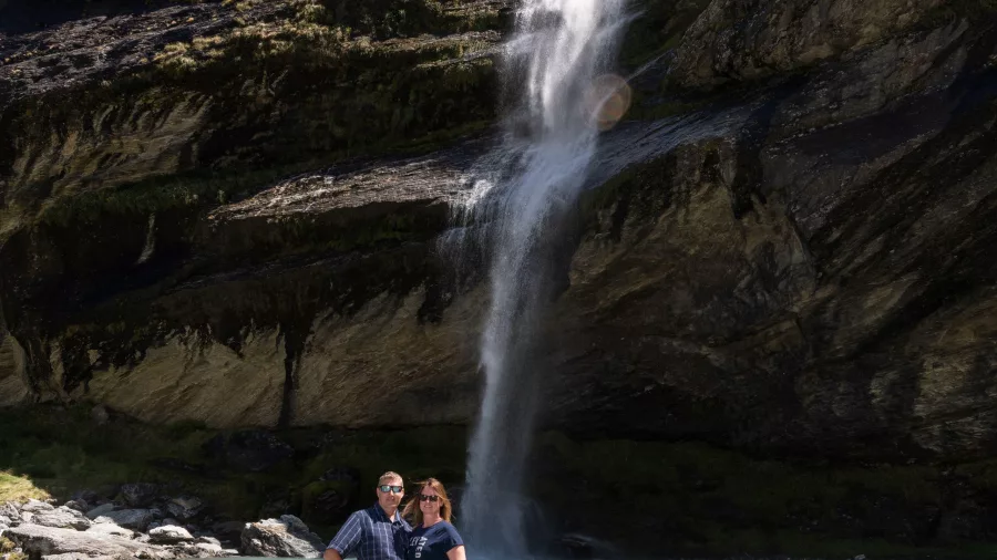 Couple standing beneath a waterfall at Earnslaw Burn