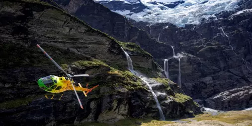 Helicopter flying near cascading waterfalls at Earnslaw Burn with Heli Glenorchy