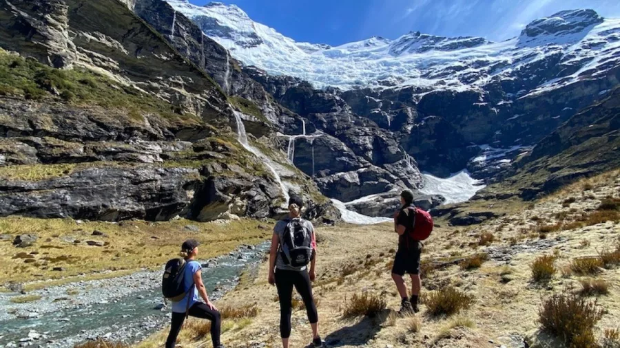 Hikers approaching Earnslaw Burn glacier and waterfalls on a heli hike