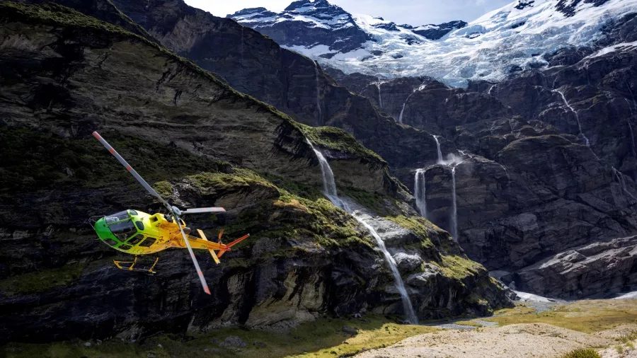 Helicopter flying into Earnslaw Burn with waterfalls and glacier in the background