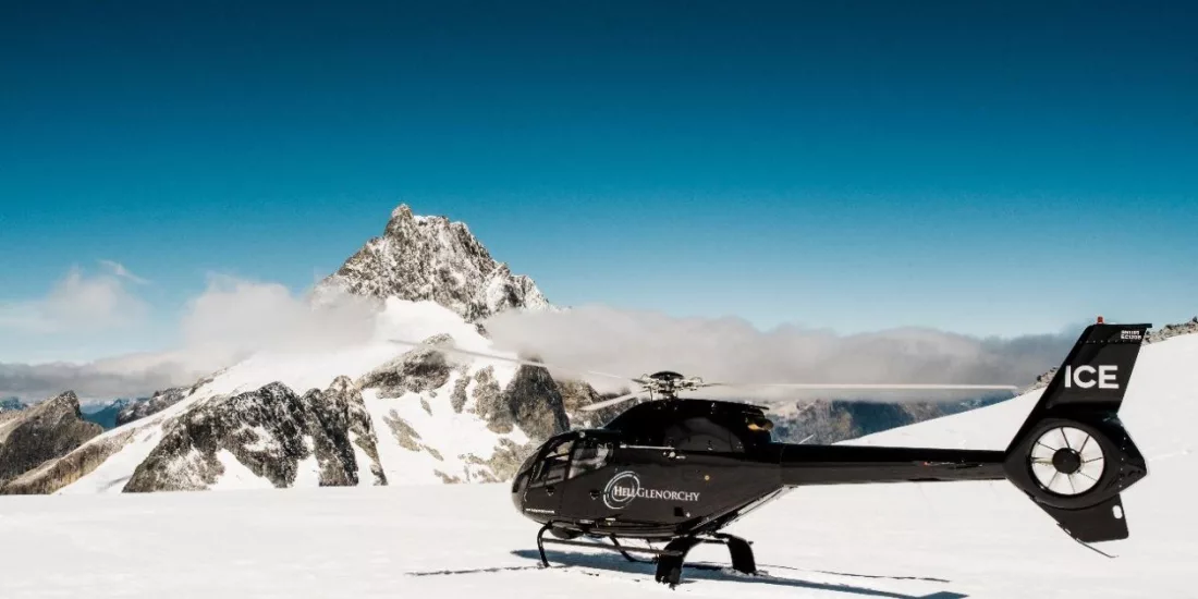 Black Heli Glenorchy helicopter parked on glacier with Mount Earnslaw in the background