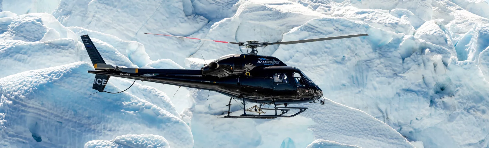 Heli Glenorchy helicopter flying over deep crevasses on Tutoko Glacier