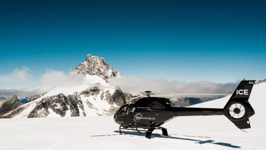 Black Heli Glenorchy helicopter parked on glacier with Mount Earnslaw in the background