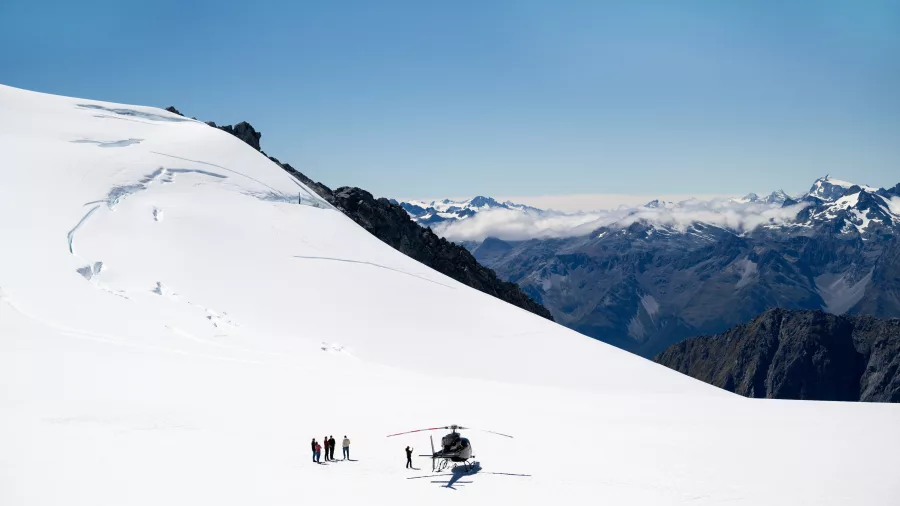 Helicopter landed on a remote snowy glacier with panoramic mountain views