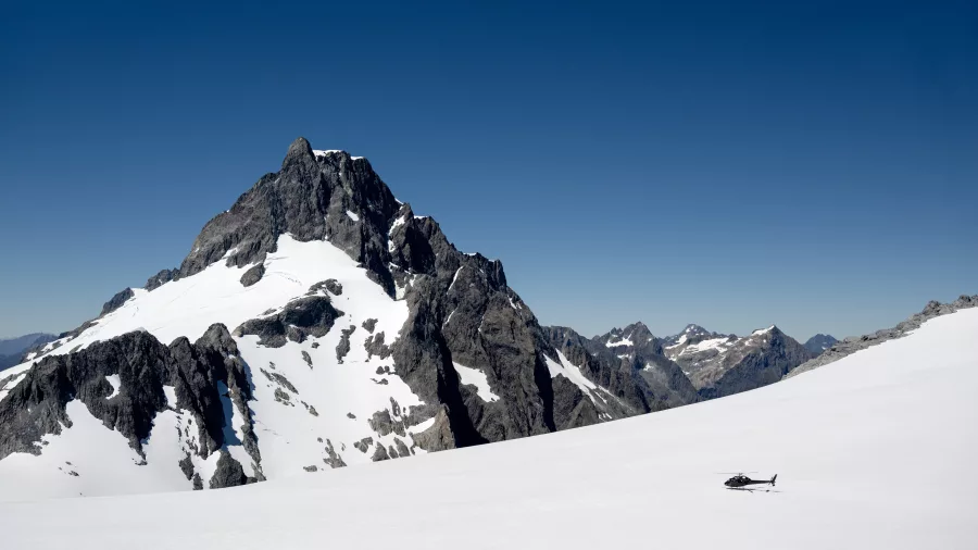 Helicopter landing on Tutoko Glacier with dramatic mountain peaks