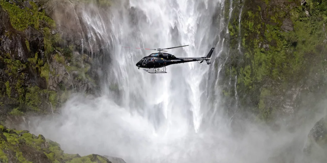 Helicopter flying close to the misty base of Sutherland Falls in Fiordland