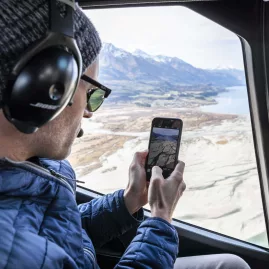 Passenger taking photos over Glenorchy from helicopter window