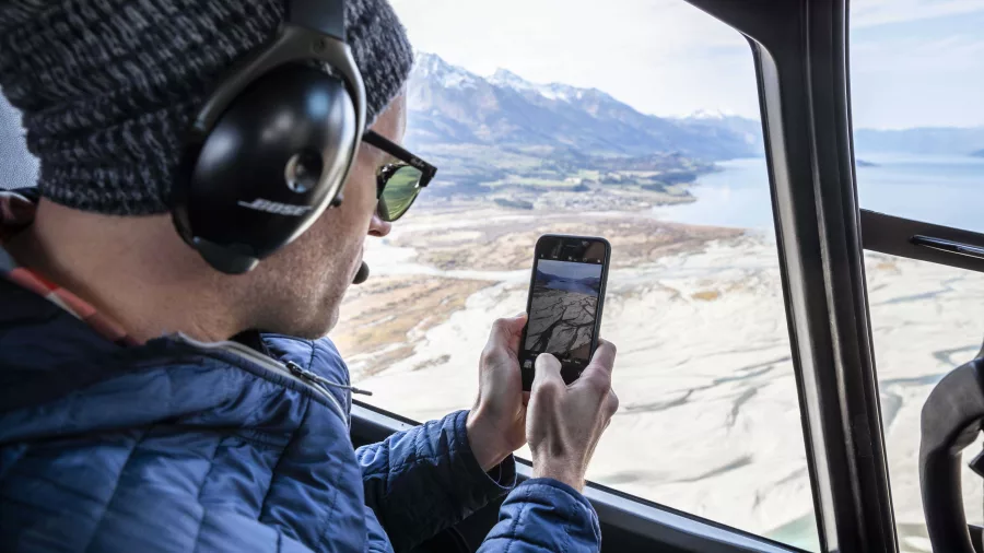 Passenger taking photos over Glenorchy from helicopter window