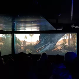 Guests watching dinosaur animation on three screens inside the Time Tripper theatre