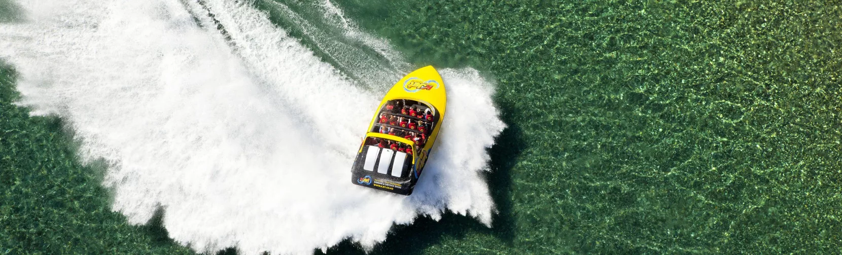 Aerial view of a KJet jet boat making a sharp turn in the shallows of Kawarau river