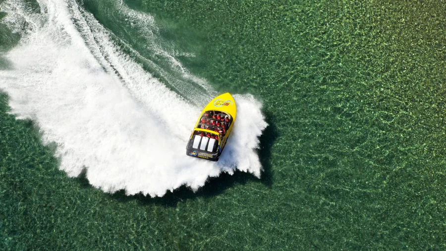Aerial view of a KJet jet boat making a sharp turn in the shallows of Kawarau river