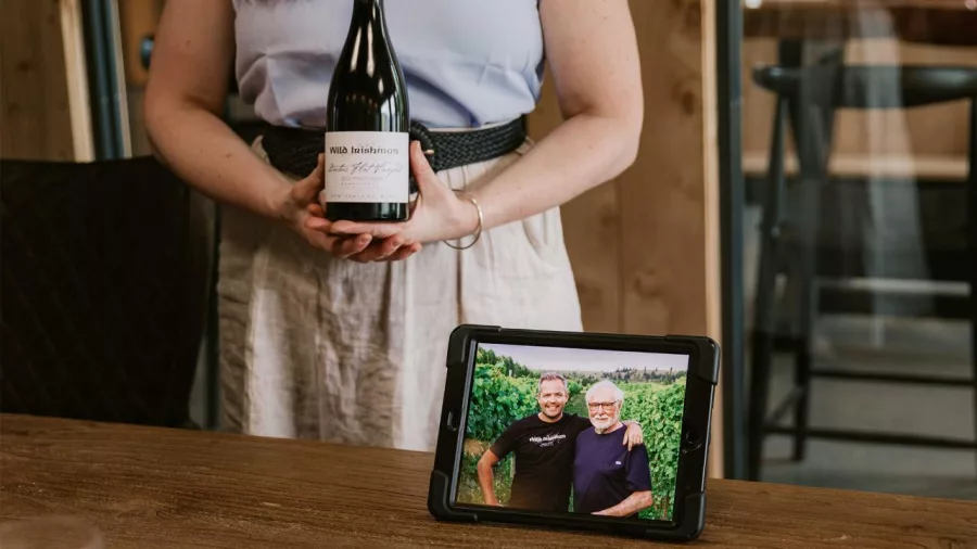 Presenter holding Wild Irishman Pinot Noir bottle next to photo of winemakers