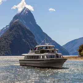 Cruise boat sailing in Milford Sound with Mitre Peak in the background