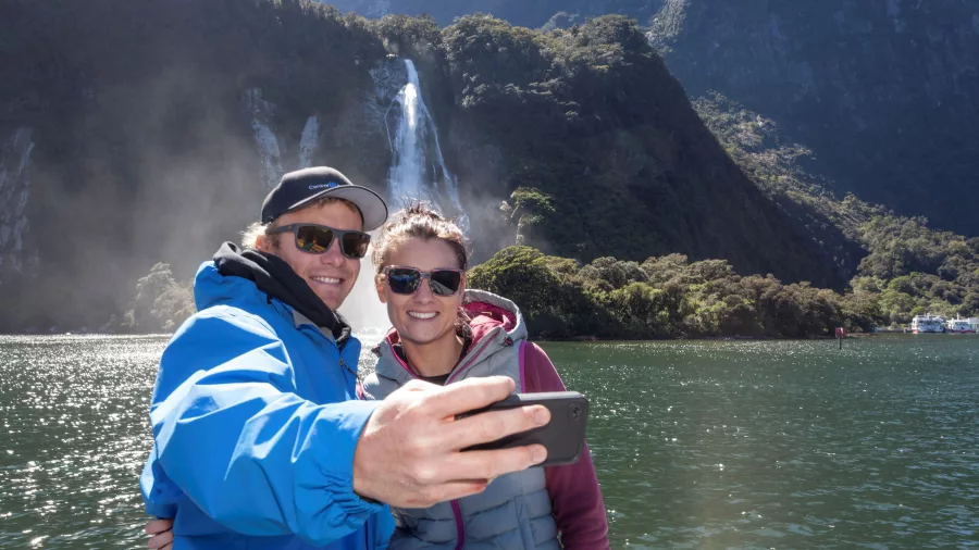 Couple taking a selfie in front of Bowen Falls in Milford Sound