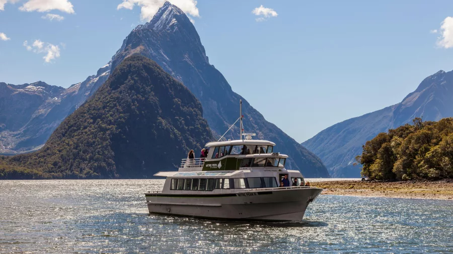 Cruise boat sailing in Milford Sound with Mitre Peak in the background
