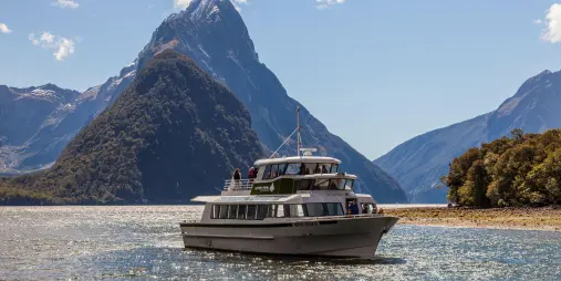 Cruise boat sailing in Milford Sound with Mitre Peak in the background