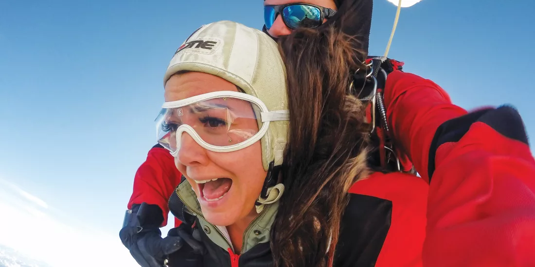 Close-up of tandem skydiver’s expression during freefall above Queenstown