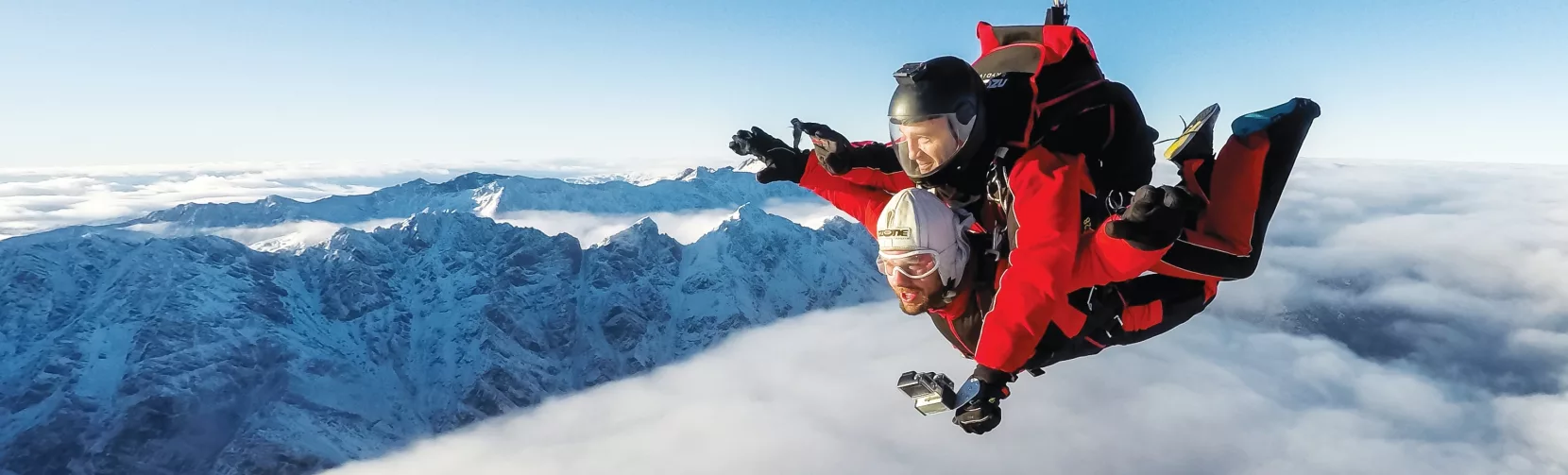 Tandem skydivers floating above the clouds near The Remarkables