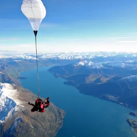 Parachute open above snow-capped mountains and Lake Wakatipu