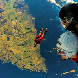 Pair of tandem skydivers over Queenstown farmland and lake views