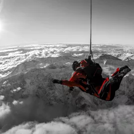 Black and white skydiving photo with red jumpsuit and cloudscape