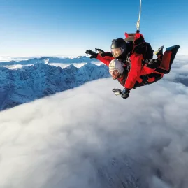 Tandem skydivers floating above the clouds near The Remarkables
